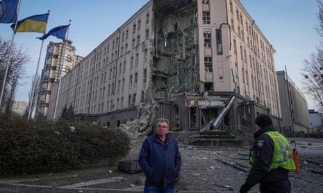 People stand in front of damaged hotel at the scene of Russian shelling in Kyiv, Ukraine, Saturday, Dec. 31, 2022.