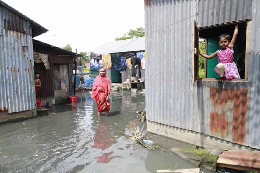 A woman stands in the polluted water that has invaded her home, at Demra in Dhaka
