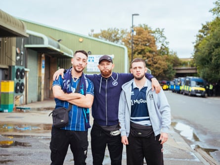 Three male Millwall supporters outside the garages by the Den