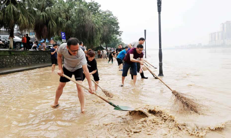 People clear a flooded street caused by heavy rains in Rongan in China's southern Guangxi region