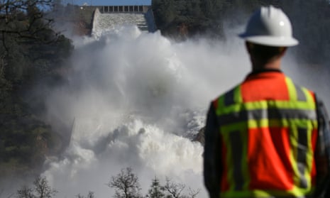 A worker keeps an eye on water coming down the damaged main spillway of the Oroville Dam on February 14, 2017 in Oroville, California. More than 188,000 people were ordered to evacuate after a hole in the emergency spillway in the Oroville Dam threatened to flood the surrounding area. 