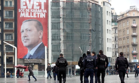People walk in front of a giant poster of Turkish Recep Tayyip Erdoğan.