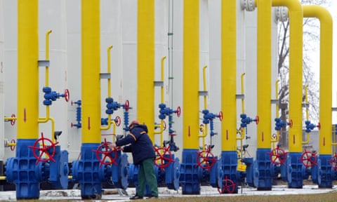 A man adjusts a control on one in a row of blue and yellow pipes