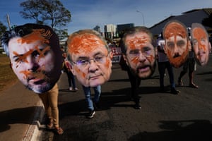 People carry cutouts of the faces of senators and march in a street