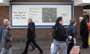 People in Ashford walk past sign announcing closure of an M&S branch