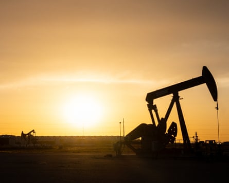 A oil pump jack is seen in shadow at sunset in Midland, Texas.
