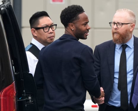 Sterling shakes hands with a bearded man as he steps out of a vehicle