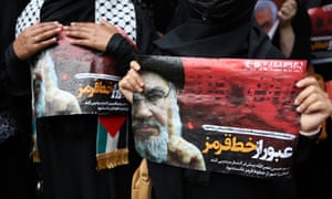 A woman's hands holding a picture of Hassan Nasrallah