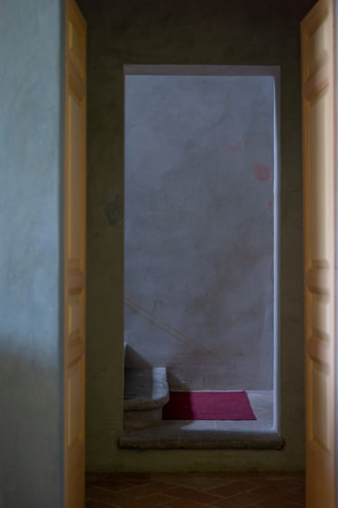 A doorway with the bottom of a staircase and a a doormat visible through it