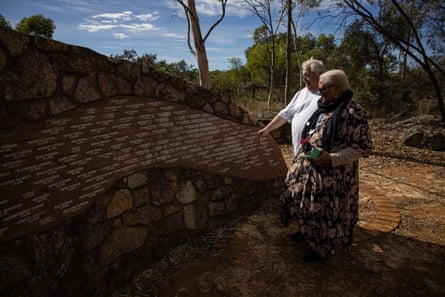 Riley and Yappo stand next to the memorial pointing at it, with small names engraved all over