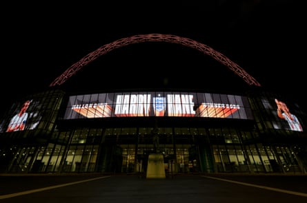 Wembley Stadium's arch lit up at night, with a screen celebrating Harry Kane's Ballon d'Or win