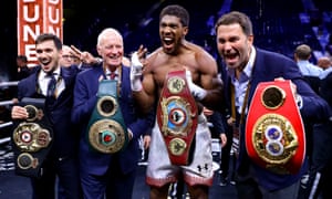 Cinturones: Anthony Joshua celebra la recuperación de sus títulos de peso pesado flanqueados por Eddie y Barry Hearn, Choque en las dunas, diciembre de 2019, Diriyah, Arabia Saudita.