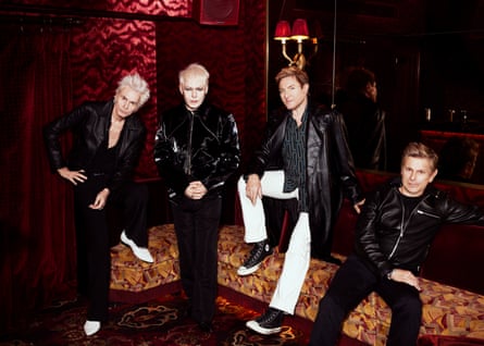 Four members of Duran Duran posing in black leather jackets in a club lounge.