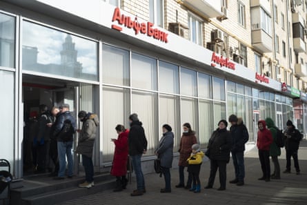 People stand in line to withdraw money from a cash machine at a bank in Moscow on 27 February 2022.