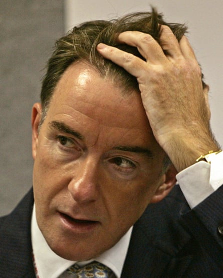 Closeup of Mandelson as he pushes his hair from his face during a meeting
