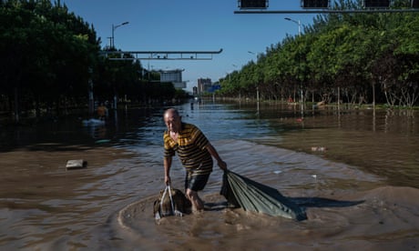 A man pulls a bag full of salvaged goods as he wades through flood waters in Zhuozhou, Hebei province, China, on Saturday