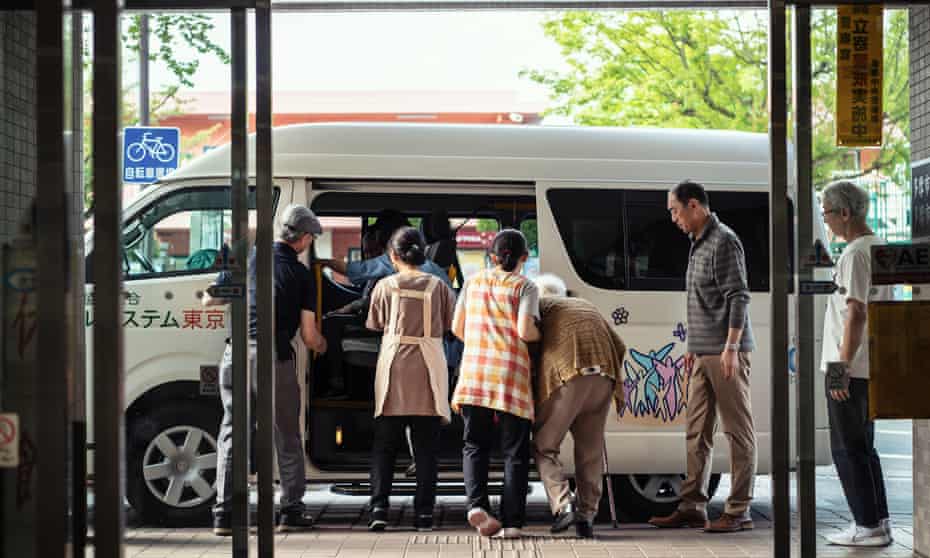 An elderly woman boards a bus from day service to home in the community centre.