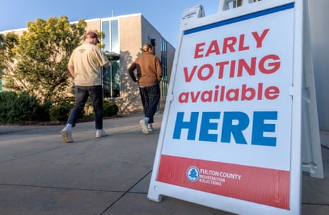 Two people walk toward a polling station past an "Early Voting" sign in Atlanta