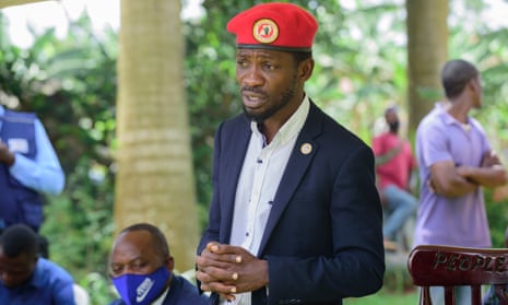 The Ugandan opposition leader Bobi Wine, wearing a dark blue suite and red beret, stands with with his hands clasped