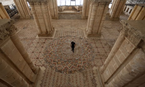 A Palestinian worker stands on mosaic panels at Hisham’s Palace