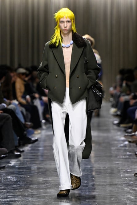 A model on the catwalk wearing white, wide-legged trousers.