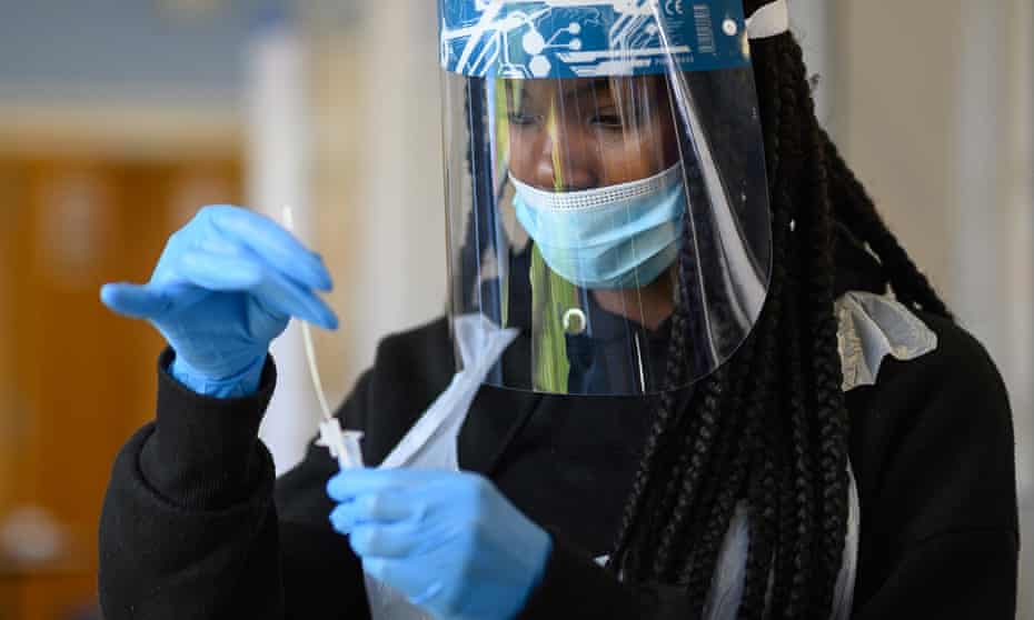 A woman in PPE processes a swab test