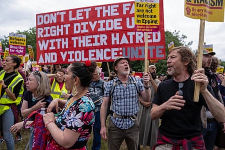 A busy scene shows men and women holding placards and signs opposing the far right as they march down a street