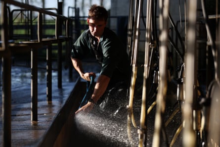 Cam Clayton, 30, cleans equipment in the shed after morning milking