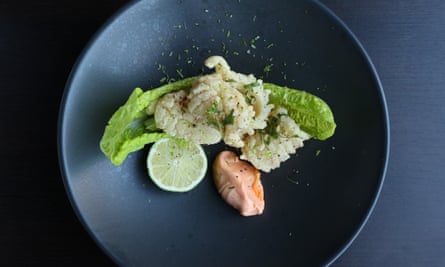 Crispy squid on a lettuce leaf with a slice of lemon and flecks of herb, on a round dark blue plate.