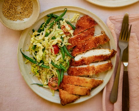 A plate on a table with a portion of panko chicken, green bean and cabbage salad