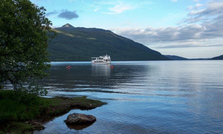 A boat glides across a glassy Loch Lomond.