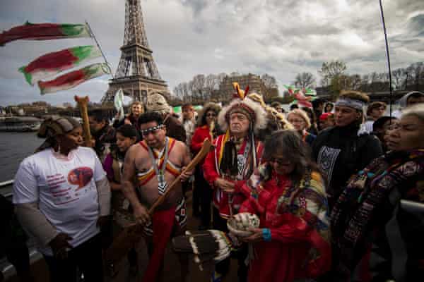 Indigenous representatives from around the world engage in a joint prayer session on board a boat in Paris