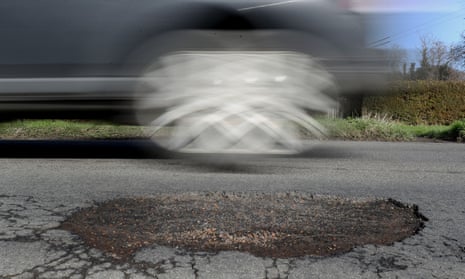 A car driving past a pothole.
