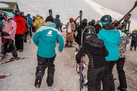 Rear view of person wearing Deliveroo jacket and snow shoes among skiiers