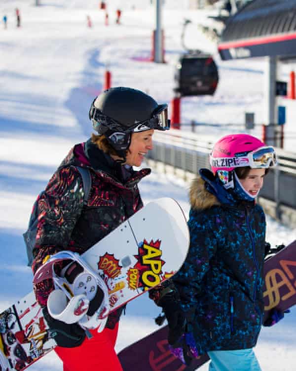 Mother and daughter carry their snowboards to the ski lift
