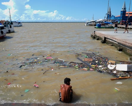 A man sits in a river amid the nearby COP30 U.N. Climate Summit, Saturday, Nov. 8, 2025, in Belem, Brazil.