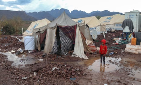 A child stands in the mud near tents at a temporary camp for people displaced by the conflict in Yemen, in the south-western province of Taiz