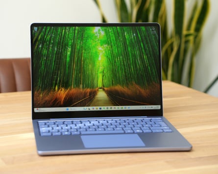 A Microsoft Surface laptop on a table in front of a plant