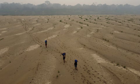 Enorme leito de rio seco com três pessoas caminhando