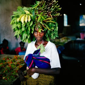 A woman carrying a basket with leaves on her head
