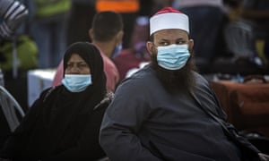 Warga Palestina yang mengenakan masker wajah duduk di samping barang bawaan mereka saat mereka menunggu untuk menyeberang ke perbatasan Rafah dengan Mesir, di Jalur Gaza selatan, Minggu, 27 September 2020.