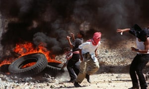 Palestinian youths flee shots by Israeli troops near Gaza City, 1 October 2000.