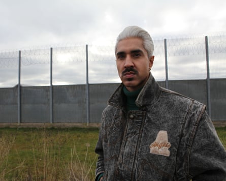 Man stands by high fence with barbed wire