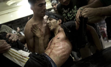 A wounded rebel fighter is carried to safety, October 2012.