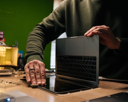 Closeup cropped shot of technician male carefully wiping screen of laptop with soft cloth, removing dust and fingerprints in professional repair shop environment. Concept of computer repairing.