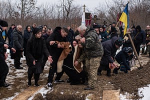 Hanna Bespalko faints after throwing soil at her son’s coffin in the cemetery of Bila Krynytsia.
