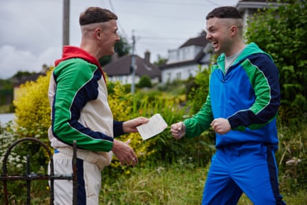 Two men in tracsuits handing over a piece of paper showing the results of a drug test to each other. They are both smiling and have a garden behind them
