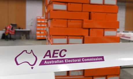 Orange boxes of senate ballot papers are stacked ready for polling booths, at an Australian Electoral Commission warehouse, behind purple and white tape with the AEC logo