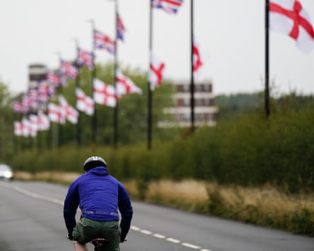 A cyclist rides past a long line of lamp-posts flying flags of St George and union jacks