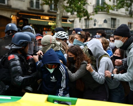 French riot gendarmes attempt to move protesters behind a barricade to block the Boulevard Saint-Germain amid clashes during a protest outside Sciences Po university in Paris.